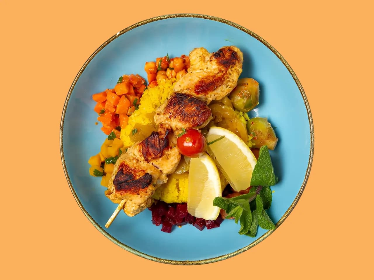 Couscous Marrakesh from above: grilled chicken skewers with lemon on a blue plate
