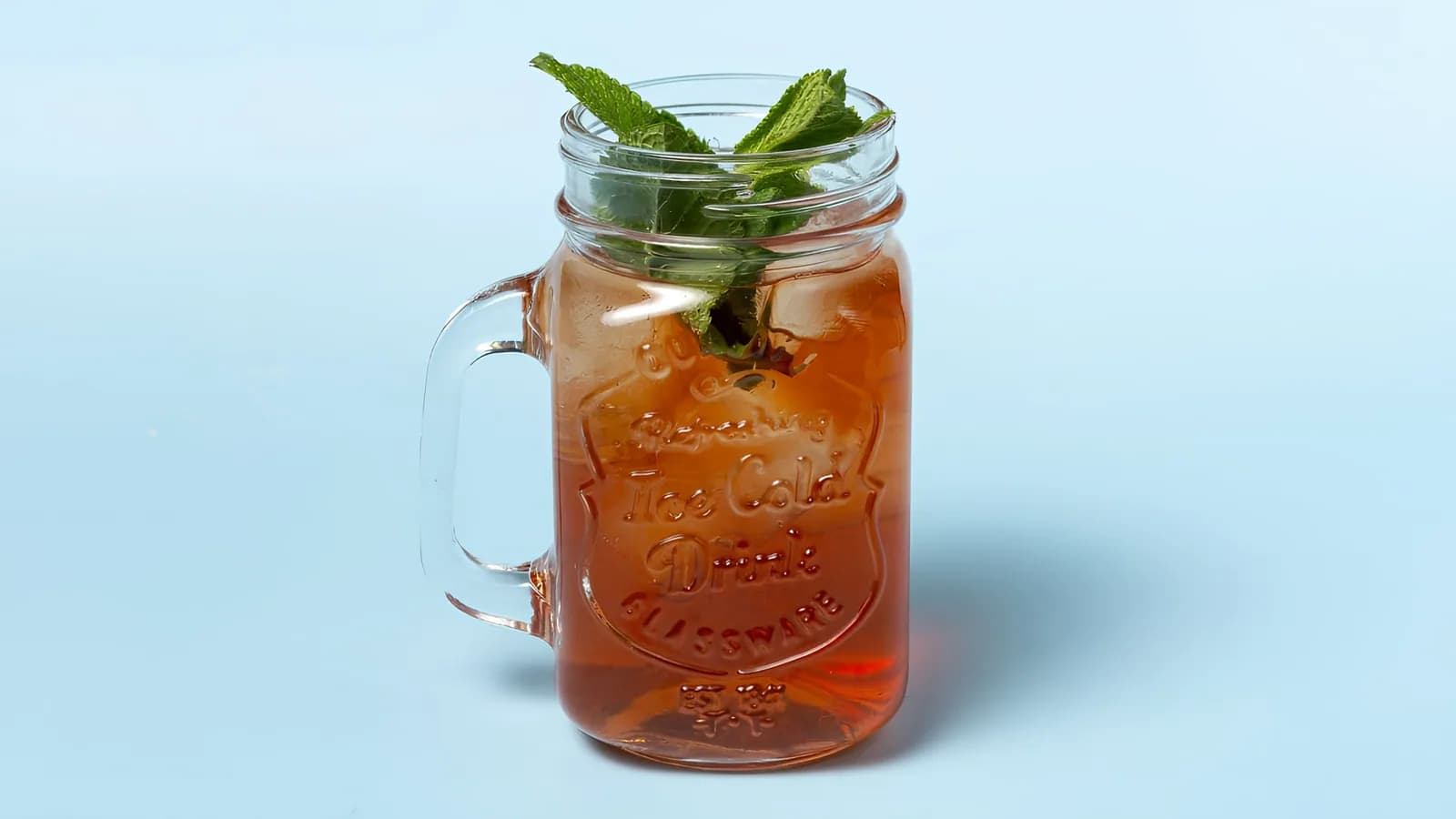 Homemade mint iced tea in a handled jar with fresh mint