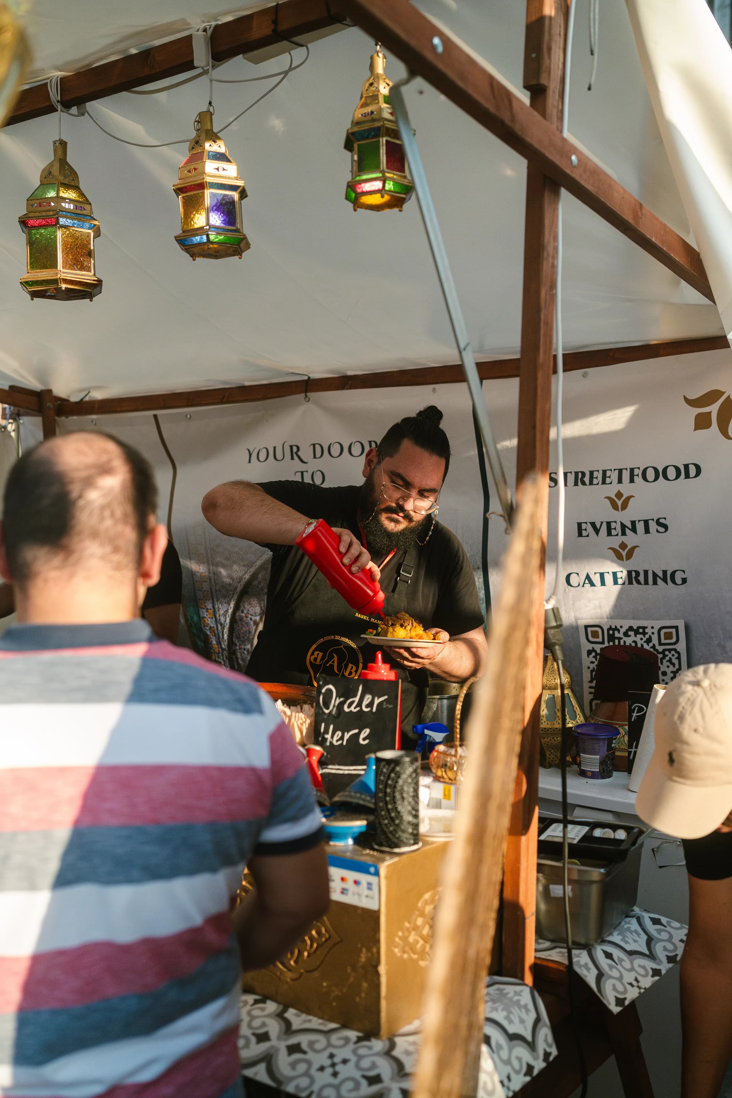 Der BAB-Stand auf einem Streetfood-Festival: marokkanische Laternen und ein Koch, der einen Teller anrichtet