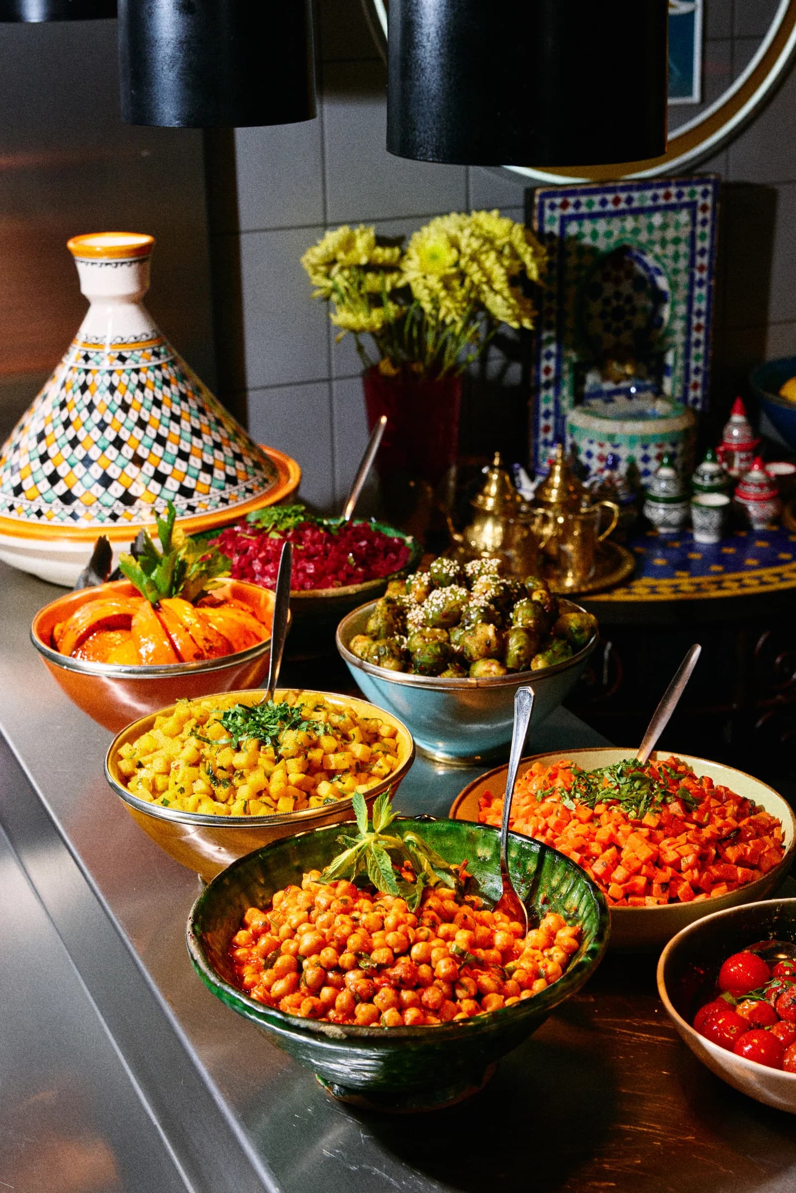 The counter lined with tajine pots and bowls of salads